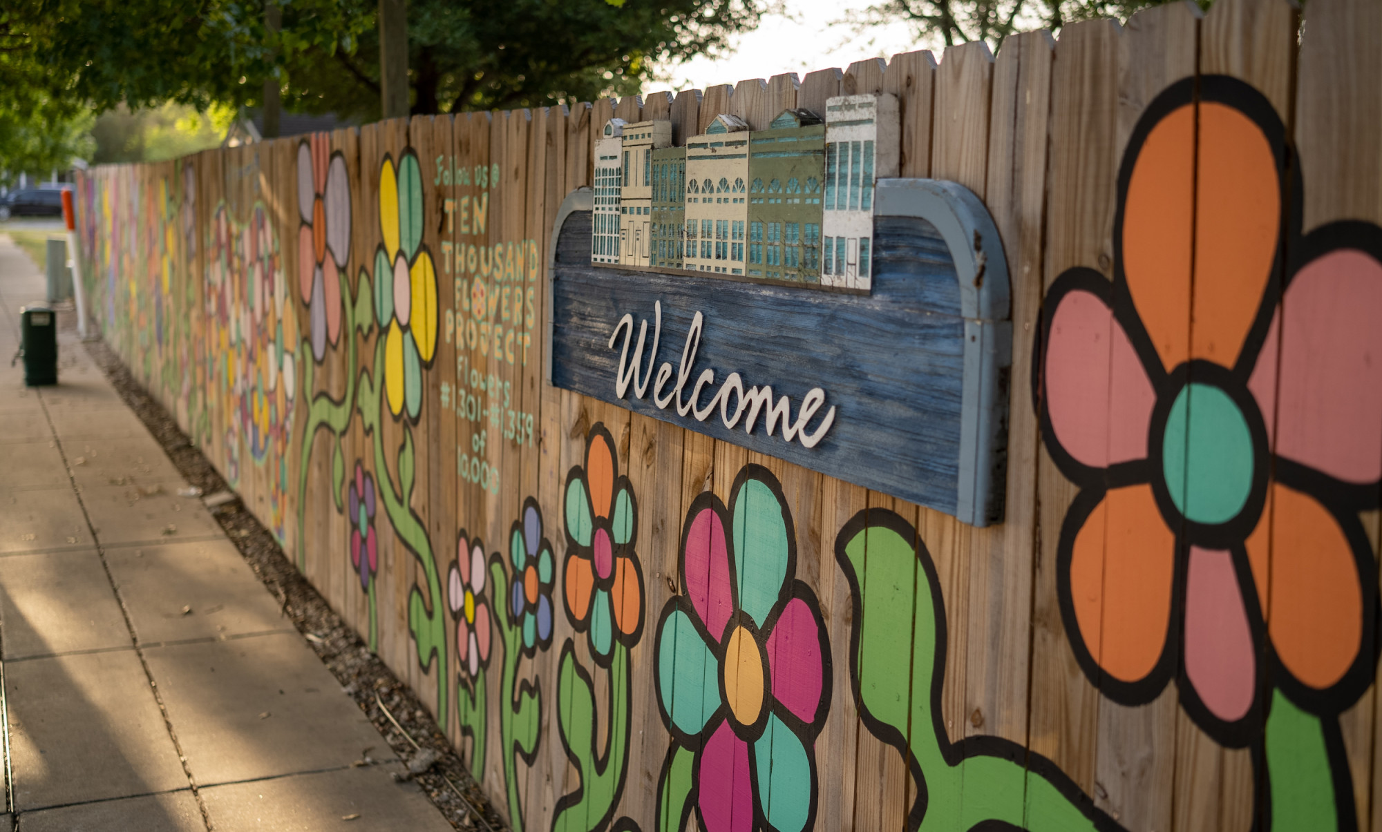 Wooden fence with welcome sign and painted flowers