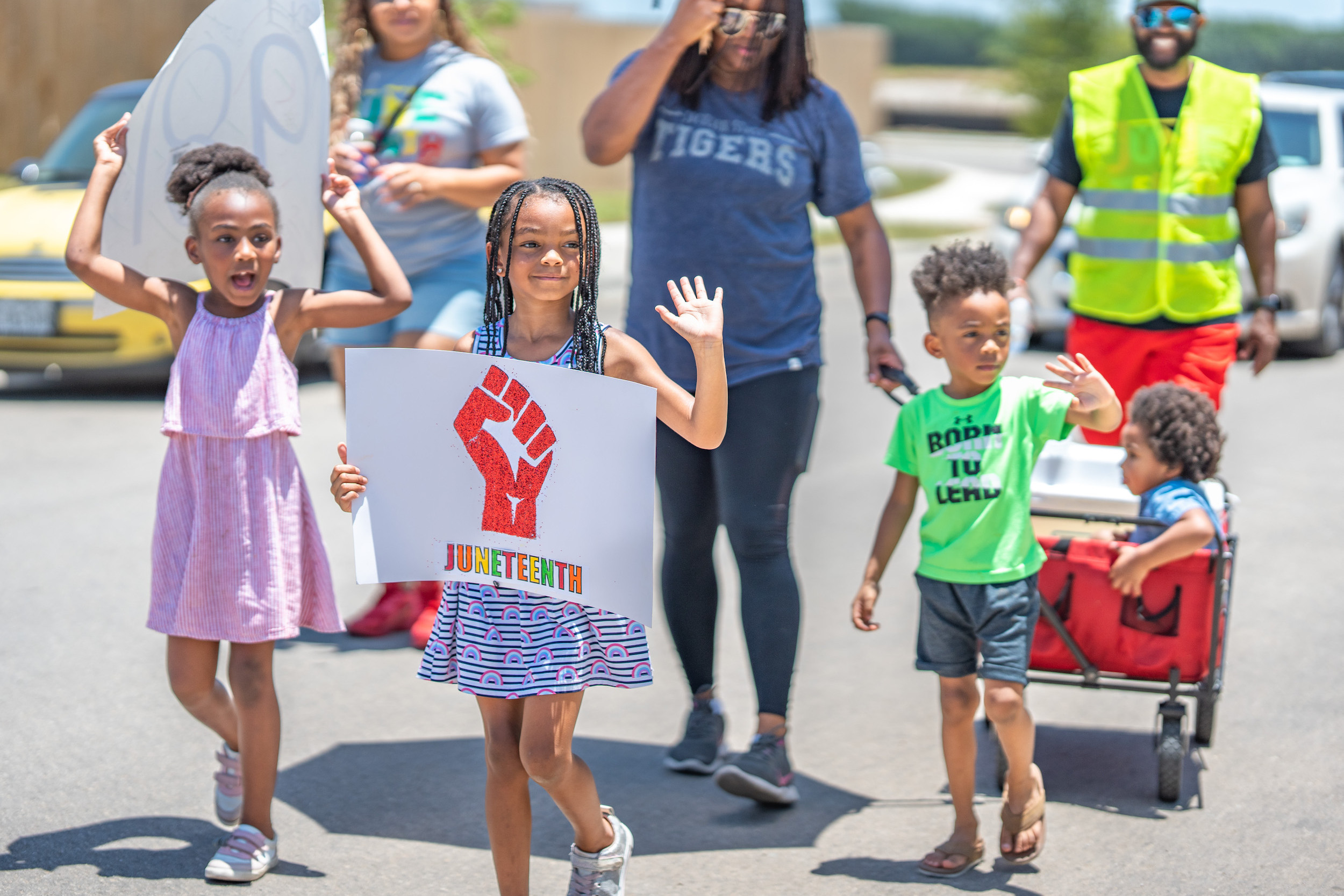 Photo of children holding Juneteenth signs in a parade.